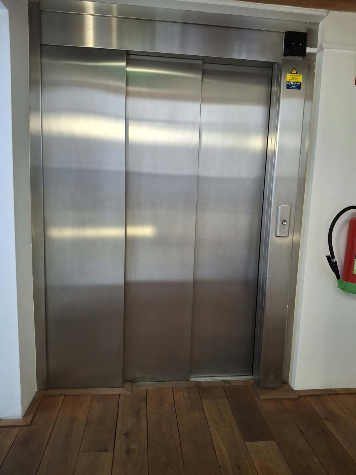 Polished stainless steel lift doors in a cleaned stairwell